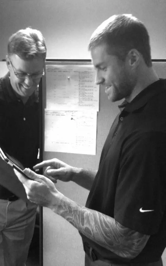 Two men looking at a tablet in black and white.