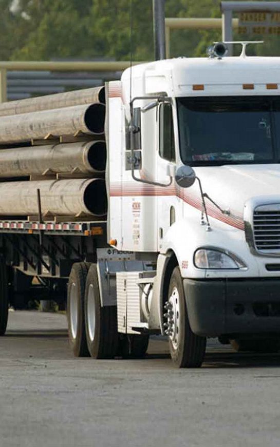 A white truck with wooden logs on the back of it.