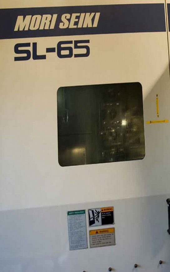 A window with Mori Seiki written above it A wall with some stickers on it