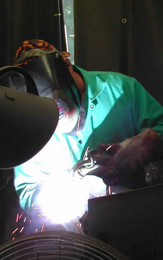 A person welding in the dark with a light shining on them.