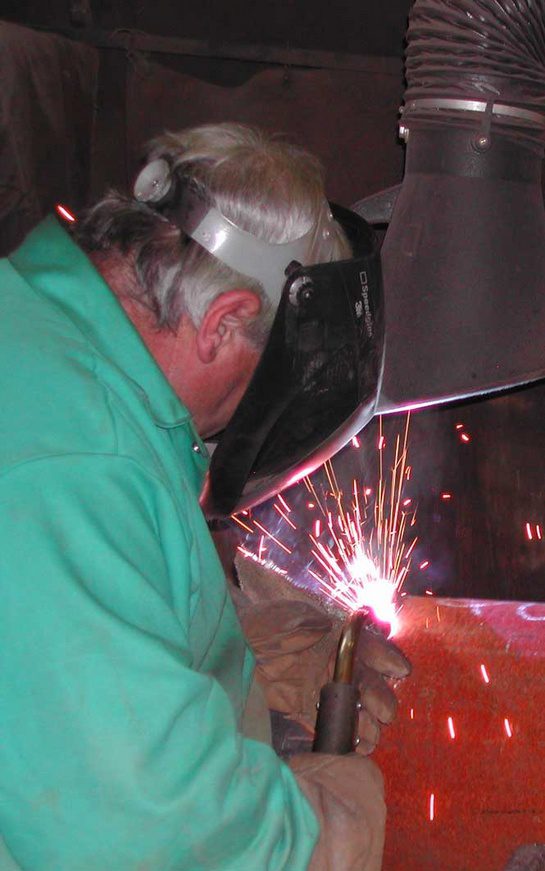A man wearing safety glasses welding metal.