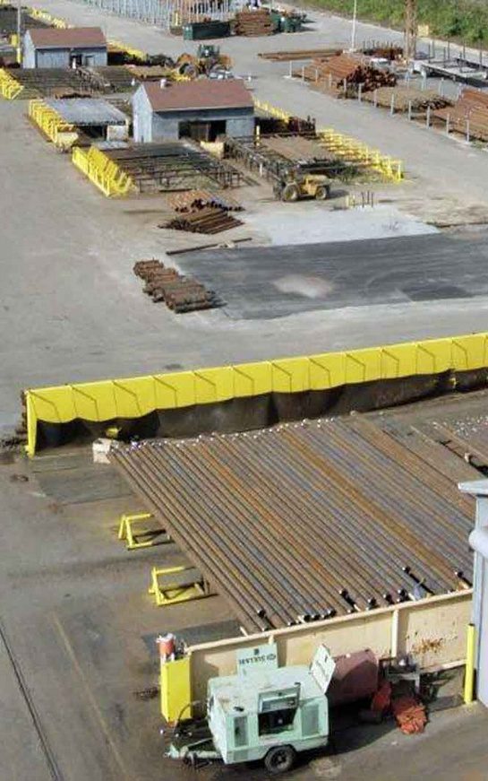 A construction site with yellow barriers and concrete.