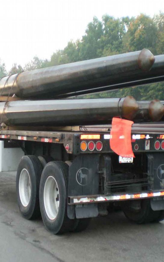 A truck with several large pipes on the back of it.