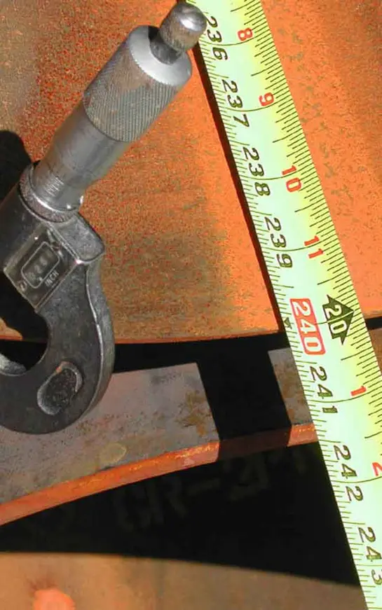 A pipe wrench and measuring tape on top of a table.