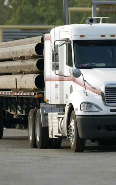 A white truck with many wooden poles on the back.