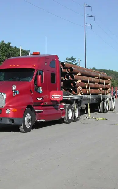 A red truck with logs on the back of it.