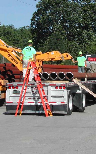 A man on a crane is standing on the back of a truck.