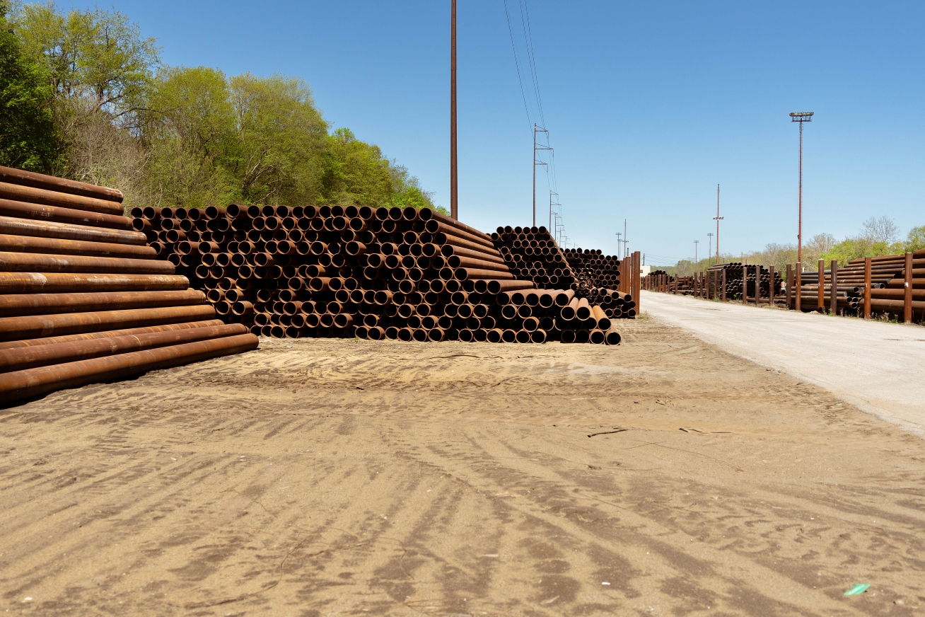 Outdoor photo of a large stack of several metal pipes